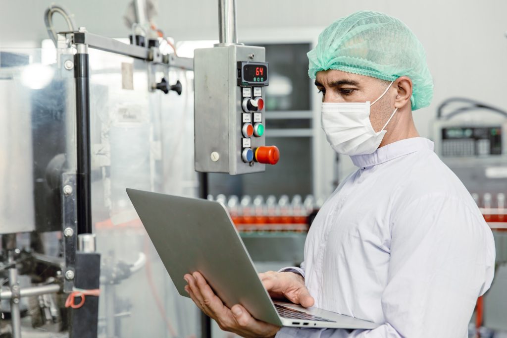 Engineer working with laptop in food factory machine production inspector with hygiene clothes.